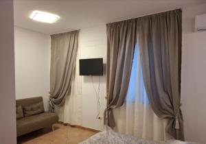 a bedroom with a window with a couch and a television at Centro mare residence affitta alloggi in Porto Torres