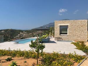a stone house with a swimming pool and an umbrella at Alos Suites in Verga Kalamata