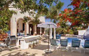 a patio with a table and chairs and an umbrella at Casa Perla de Todos Santos in Todos Santos