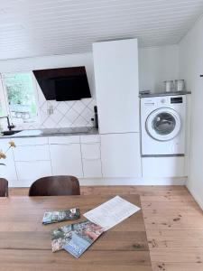 a kitchen with a washing machine and a wooden table at Det lille hus in Viborg
