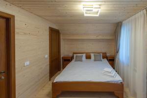 ein Schlafzimmer mit einem Bett in einem Holzzimmer in der Unterkunft Arhondaric in Rucăr