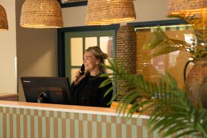 een vrouw die aan een balie zit en via een microfoon praat bij Forest Hotel in Den Helder