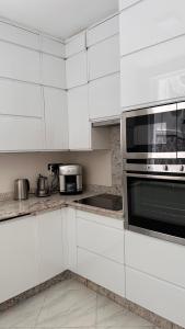 a kitchen with white cabinets and a microwave at Riad Darabi l Private Medina Home in Marrakesh
