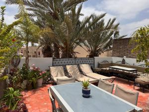 a patio with a table and chairs and palm trees at Riad Darabi l Private Medina Home in Marrakesh