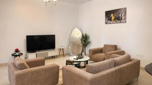 a living room with two chairs and a flat screen tv at Lake View By Bait Zain in As Sīfah