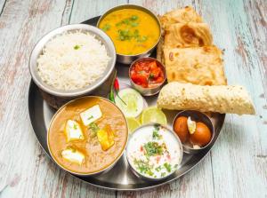 a plate of food with rice and different types of food at Hotel Rosewood Suites Near Delhi IGI Airport in New Delhi +26 photos