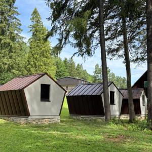 a couple of buildings in a field with trees at Glamping chatky in Spišské Tomášovce