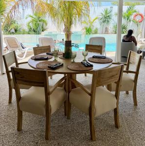 a dining room table with chairs and a pool at Villa Chanalu in Ngaparou