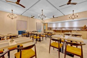 a restaurant with tables and chairs and a kitchen at Hotel Cachet in Coimbatore