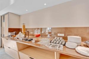 a kitchen with a counter with plates and food at Hotel Cachet in Coimbatore +47 photos