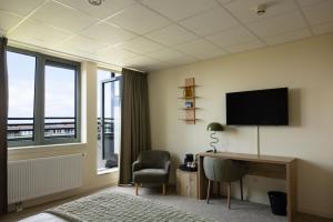 een kamer met een bureau met een televisie en een stoel bij Forest Hotel in Den Helder