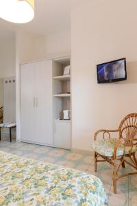a bedroom with a bed and a chair and a tv at Residence delle Nazioni - Spiaggia privata su richiesta in Principina a Mare