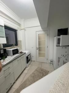a white kitchen with a microwave and a refrigerator at Solid House Apartment - Sea View in Mamaia +4 photos