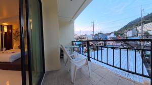 a balcony with a white chair and a view at Azure Stays Patong in Patong Beach