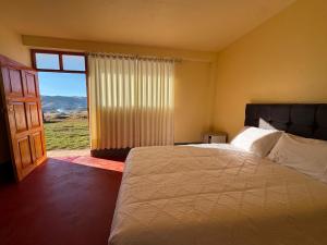 a bedroom with a bed and a large window at Casa Cóndor Ausangate in Tinke
