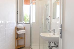 a white bathroom with a sink and a shower at Residence delle Nazioni - Spiaggia privata su richiesta in Principina a Mare +158 photos