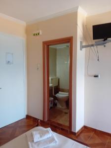 a bathroom with a toilet and a tv on the wall at FAFALIOS Studios in Vrontádos