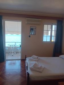 a bedroom with a bed and a balcony with a table at FAFALIOS Studios in Vrontádos