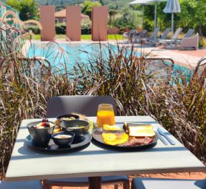 ein Teller mit Frühstücksessen auf einem Tisch neben einem Pool in der Unterkunft Cape Resort in Peroulades