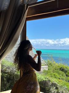 a woman looking out of a window at the ocean at Tao Resort in Andavakonko