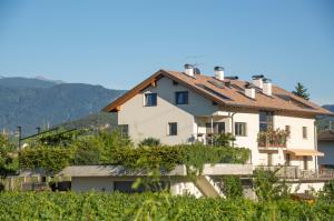 a large white house with a bunch of vines at Ferienwohnungen Tollhof - Near Bolzano and castles, with a guest card for families and couples, offering panoramic views in Cornaiano