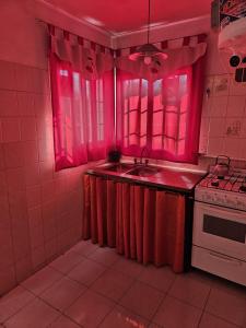 a pink kitchen with a sink and a stove at Terraza Perito Moreno in Villa Carlos Paz