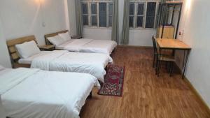 a room with three beds and a table and a desk at Hotel Baishnav, Mugling in Upardāng Garhi
