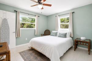 a bedroom with a white bed and two windows at The Crystal River House in Crystal River