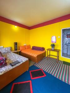 a room with two beds and a yellow wall at Dawaipani Sona Homestay in Jālāpahār