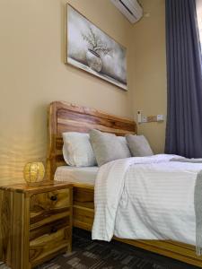 a bedroom with a wooden bed with white sheets at HM Homes in Morogoro