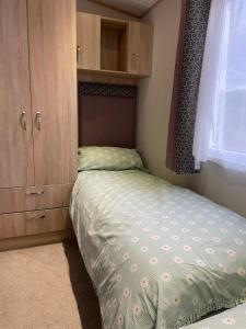 a small bedroom with a bed and a cabinet at Sunset View - with view of the lighthouse and a shower and bath in Lossiemouth +6 photos