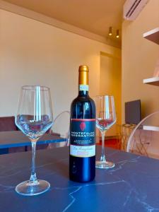 a bottle of wine and two wine glasses on a table at Augusta e Libero Apartments in Spoleto
