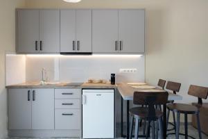 a kitchen with white cabinets and a table with stools at Maria Anastasia Studios in Trapezaki +57 photos