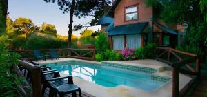 a house with a swimming pool in front of a house at Cabañas Murmullo de Agua in Mar de las Pampas