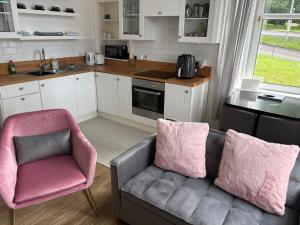 a living room with a couch and a pink chair at Our Wee Eden - Rothesay in Rothesay