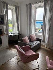 a living room with a couch and a chair and windows at Our Wee Eden - Rothesay in Rothesay