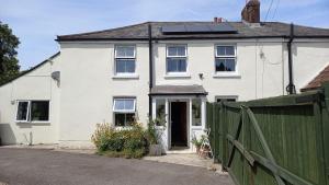 a white house with a green fence in front of it at The Post Office, 6 beds, Bar, Library, Pool Table, Stream, Large Garden in Piddletrenthide