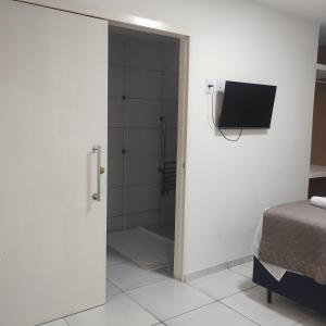 a bathroom with a shower and a tv on a wall at Pousada Mangai in João Pessoa