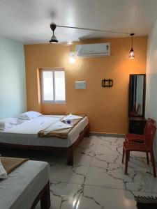 a bedroom with two beds and a chair in it at Relax Residency in Mandapam +3 photos