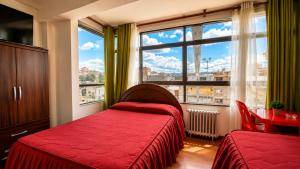 a bedroom with a red bed and a large window at Hotel Beirut Oruro in Oruro
