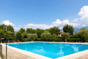 a blue swimming pool with trees and mountains in the background at Residence The Yellow Fish with Pool in Manerba del Garda