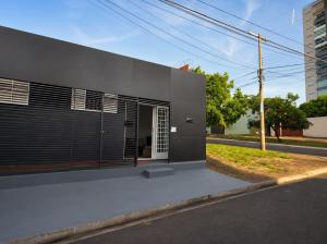 a building with black shutters on the side of a street at Pousada da Juh in Campo Grande