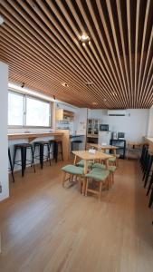 a room with tables and chairs and a wooden ceiling at Poly Hostel 2 Namba in Osaka