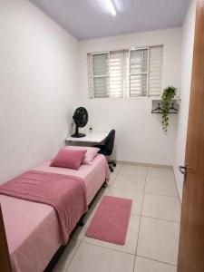 a bedroom with two beds and a desk and window at Pousada da Juh in Campo Grande