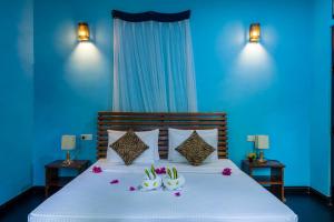 a blue bedroom with a bed with flowers on it at Sigiri Siesta Homestay in Sigiriya