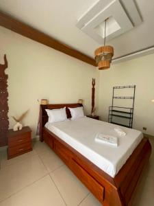a bedroom with a large wooden bed with white sheets at Villa REEL in Morondava