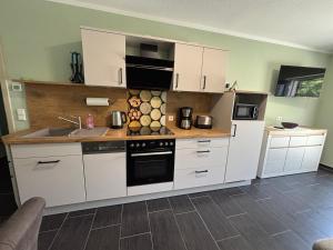 a kitchen with white cabinets and a stove top oven at Ferienwohnung Grüne Oase in Lübbenau