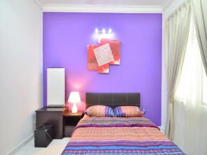 Dormitorio con pared morada, cama y escritorio en Johar Jantan Apartment en Shah Alam