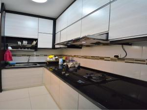 cocina con armarios blancos y encimera negra en Johar Jantan Apartment, en Shah Alam