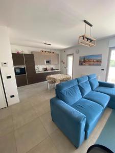 a living room with a blue couch and a kitchen at Brezza di Bari, Terrace & Free Parking, family and group apartment by Leviora Collection in Bari